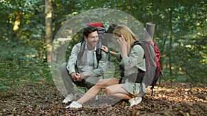 Anti mosquitos protection. Caring man spraying repellent from bottle on woman leg, taking care about her during hiking