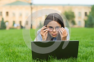 Anti-reflective coating glasses. online education. back to school. teen girl use computer in park. child in glasses with