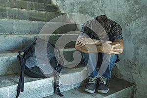 Campaign vs homophobia with young sad and depressed college student man sitting on staircase desperate victim of harassment photo