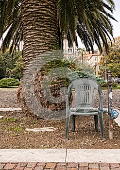 Anti theft device - chair padlocked to post. Under palm tree.