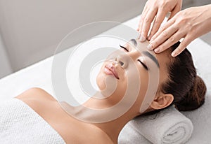 Anti-wrinkle massage. Young Asian woman relaxing during beauty treatment in spa salon