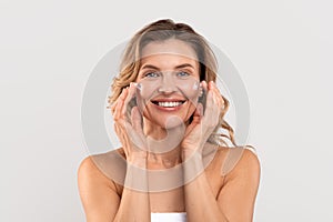 Antiage Treatment. Beautiful Caucasian Woman Applying Moisturizing Cream On Face