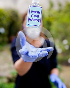 Antibacterial gel in NHS nurse hand - WASH YOUR HANDS photo