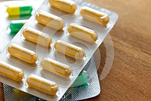 Antibiotic capsule drugs in the packaging on wood background.