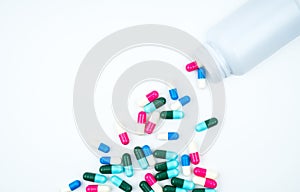 Antibiotic capsules spilling out of pill bottle on white background with copy space