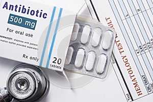 Antibiotic drug. Open paper packaging box of medication with name group of drug Antibiotic, blister with pills, next to stethoscop photo