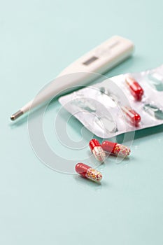 Antibiotic and thermometer. Highly blurred background photo