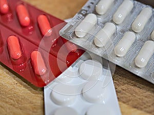 Antibiotics pills and capsules in blister pack closeup on flat wooden surface. antimicrobial pharmacy, painkillers. red and white