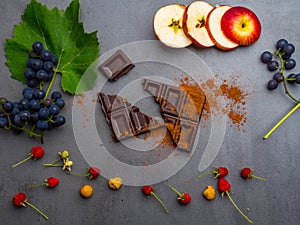 anticancer food, good for cardiovasculas system, fresh ripe grape, raspberries, dark chocolate, cocoa, apple slices on concrete