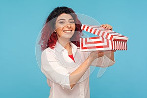 In anticipation of surprise. Portrait of attractive hipster woman with fancy red hair holding opened gift box