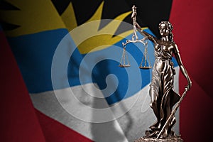 Antigua and Barbuda flag with statue of lady justice and judicial scales in dark room. Concept of judgement and