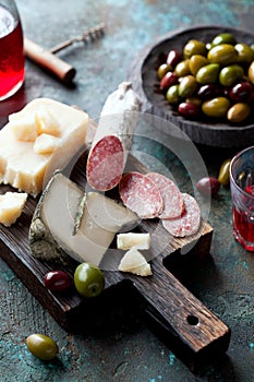 Antipasto board with sliced salami, goat cheese, assorted olives and red wine