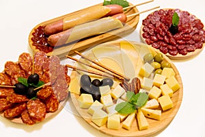 Antipasto platter assorted sliced cheeses, sausages, salami with olives and crackers on wooden plates. Appetizer, catering food
