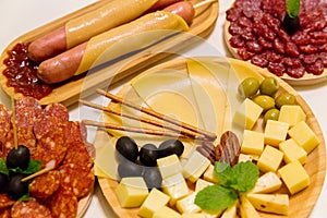 Antipasto platter assorted sliced cheeses, sausages, salami with olives and crackers on wooden plates. Appetizer, catering food