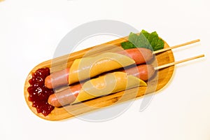 Antipasto platter boiled Frankfurter sausages with sauce on a wooden plate with cheese and mint over white background. Appetizer,