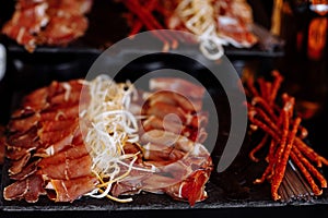 Antipasto platter cold meat, prosciutto, slices ham, beef jerky, salami and cheese platter on gray background. Closeup of beer