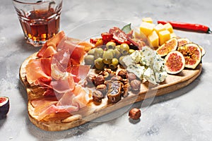Antipasto platter with ham, prosciutto, blue cheese, dried tomatoes, figs and olives on a wooden bord
