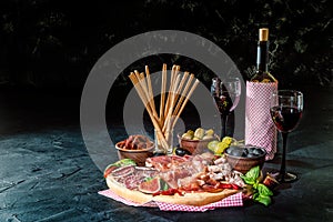 Antipasto platter with ham, prosciutto, salami, blue cheese, mozzarella, olives, grissini bread sticks with pesto