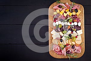 Antipasto platter with ham, prosciutto, salami, cheese,  crackers and olives on a wooden background.