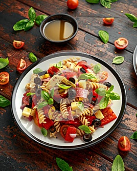 Antipasto salad with pasta, tomato, olives, red onion, bell pepper, salami, cheese, artichoke and basil