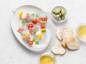 Antipasto skewers. Mediterranean appetizer to wine - prosciutto, bell peppers, cherry tomatoes, mozzarella cheese on skewers and w