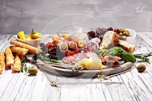 Antipasto various appetizer. Cutting board with prosciutto, salami, cheese, bread and olives on white wooden background