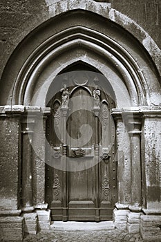 Antique arch and portal of a cathedral with a massive wooden door