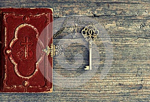 Antique bible book and golden key on wooden background