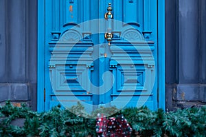 Antique blue door with ornate brass handle and distressed wooden panels