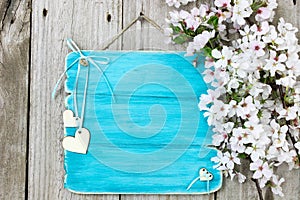 Antique blue sign with white flowers and wood hearts hanging on wooden fence