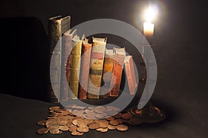 Antique books with coins and candle