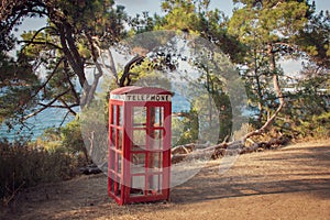 Antique British telephone booth as a famous image set up in a forest park by the sea.