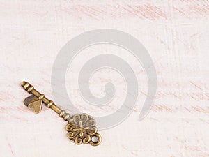 Antique bronze key on light brown wooden background