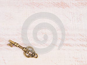 Antique bronze key on light brown wooden background