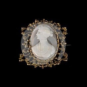 Antique brooch with a female profile in a gold frame. antique brooch on a black isolated background