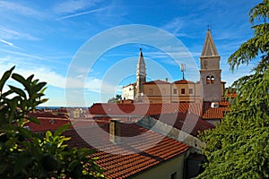 Buildings and trees in the city of Piran, Eslovenia with a church and a blue sky in the background. photo