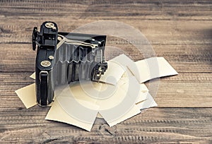 Antique camera and old photos on wooden background