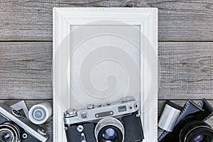 Antique cameras, negative films and white empty photo frame on w