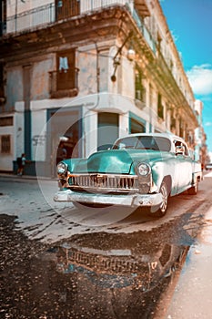 Antique car with reflections on a water puddle in Old Havana