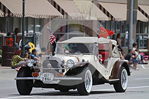 Antique car with roof with American Flags in parade in small town America