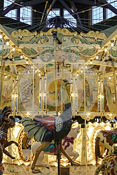 An antique carousel with an inticate ostrich carving below and mechanical systems visible overhead