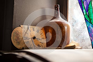 Antique Clock and the old bottle near a window wall