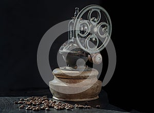 Antique coffee bean original grinder metal shake wheel with hand crank and coffee beans on dark background