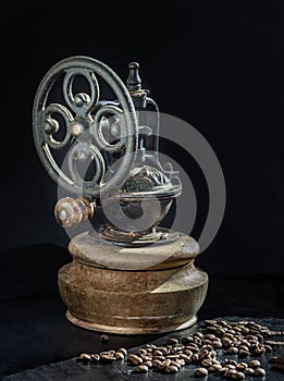 Antique coffee original grinder metal shake wheel with hand crank and coffee beans on dark background