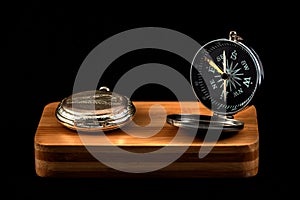 antique compass and pocket watch on wood with black background
