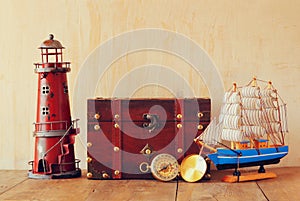 Antique compass, vintage lighthouse, wooden boat and old chest on wooden table