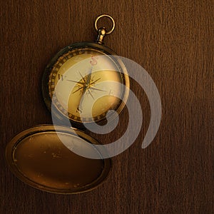 Antique compass on a wooden table with the north replaced by the dollar sign in top view. 3D illustration of an old metal compass