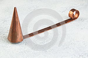 Antique copper candle snuffer on concrete background