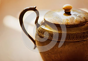 The antique copper elegant teapot is illuminated by a bright warm light. Genie`s magic lamp. Asian old gold pot