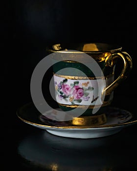 Antique cup painted with flowers and gold with a saucer